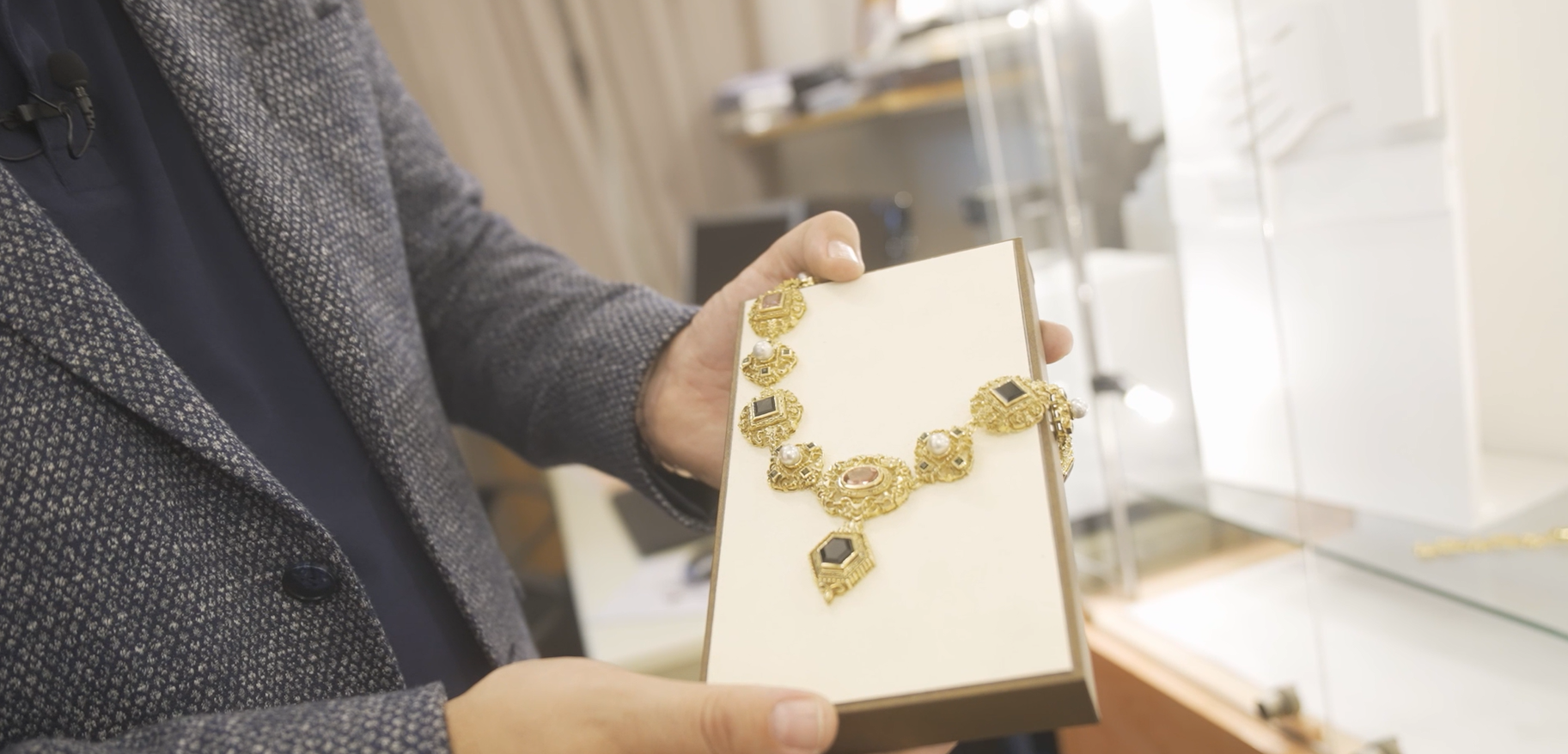 Das Bild zeigt eine alte schwere Goldkette, die mit Perlen und Edelsteinen besetzt ist und von einem Mitarbeiter*in der Alten Silberschmiede präsentiert wird. Foto von Andreas Horvath
