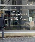 Außenansicht der Veganen Fleischerei Augsburg mit Logo im Schaufenster, Kreidetafel-Speisekarte und einem Passanten vor dem Eingang. 