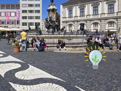 Der Augustusbrunnen auf dem Rathaus. Menschen sitzen auf den Stufen und genießen die Sonne. Foto: Norbert Liesz