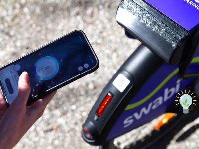 Das Bild von Thomas Hosemann zeigt den hinteren Teil eines Swabi Leihfahrrads mit einem QR Codes auf dem Schutzblech. Eine Person mit einem Smartphone in der Hand scannt er diesen ab. 