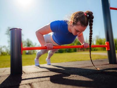 Junge Frau trainiert in einen Outdoor-Fitnesspark