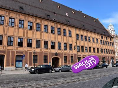 Das Bild zeigt eine Außenansicht des Fugger Stadtpalastes mit geparkten Autos im Vordergrund. Bild von der Regio Tourismus Augsburg