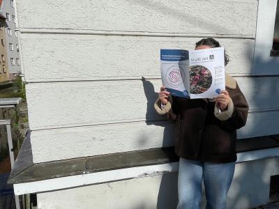 Frau liest Agendazeitung Stadt mit A