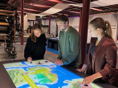 Foto zeigt den neuen digitalen Spieltisch im Textil- und Industriemuseum Augsburg. Drei Personen bedienen gerade das Spiel, um es vorzustellen. Sie haben  das Spiel mitentwickelt.