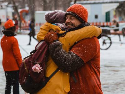 Zwei Menschen umarmen sich im Schnee auf einem Platz in Augsburg.