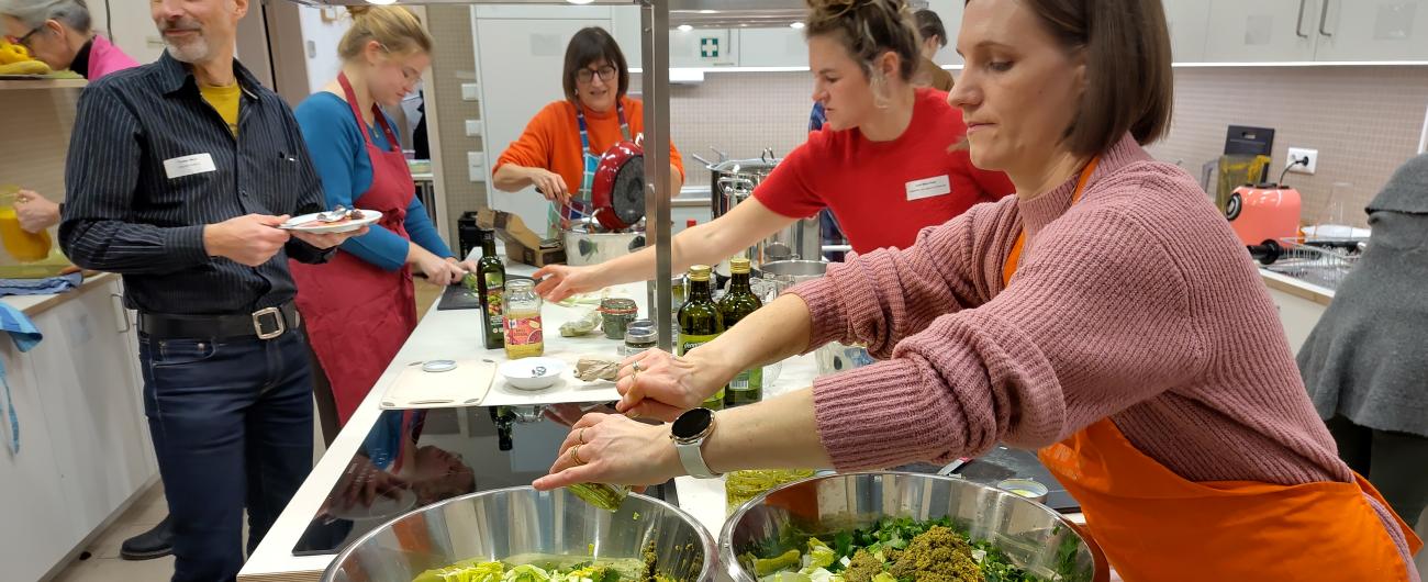 Menschen auf der Lifeguide Netzwerkparty helfen alle beim Schnibbeln von geretteten Lebensmitteln. Foto: Christina Hausotter.
