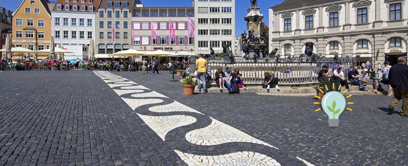 Der Augustusbrunnen auf dem Rathaus. Menschen sitzen auf den Stufen und genießen die Sonne. Foto: Norbert Liesz