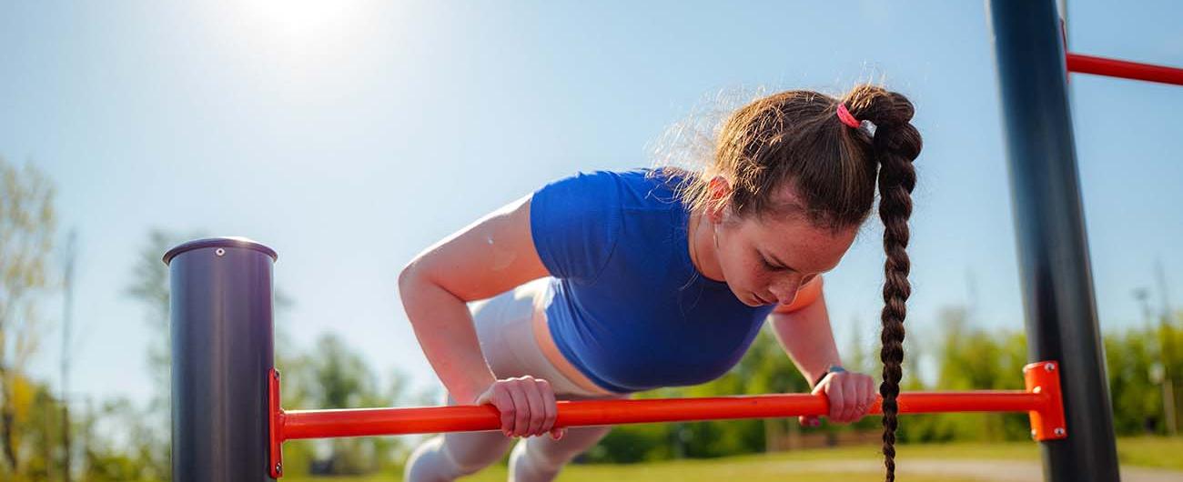 Junge Frau trainiert in einen Outdoor-Fitnesspark
