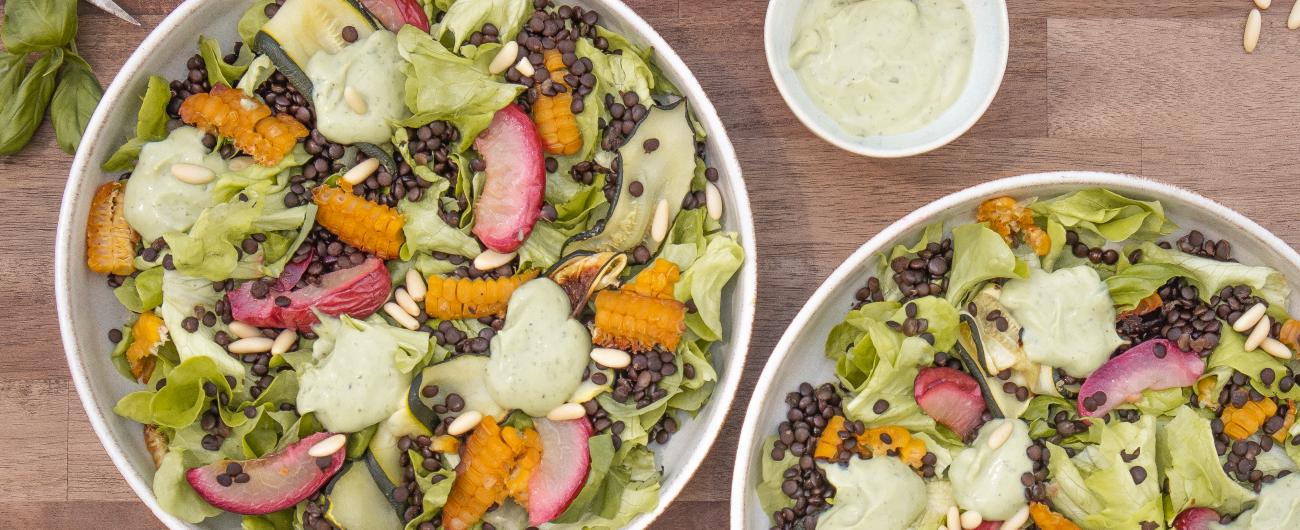 Das Bild zeigt einen bunten Salat mit grünem Salat, dunklen Linsen, grünen Zucchini und rotweißen Nektarinen. Bild Oekokiste e.V.