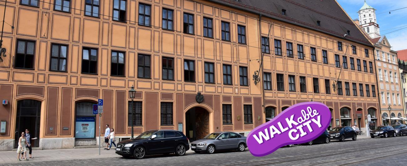 Das Bild zeigt eine Außenansicht des Fugger Stadtpalastes mit geparkten Autos im Vordergrund. Bild von der Regio Tourismus Augsburg