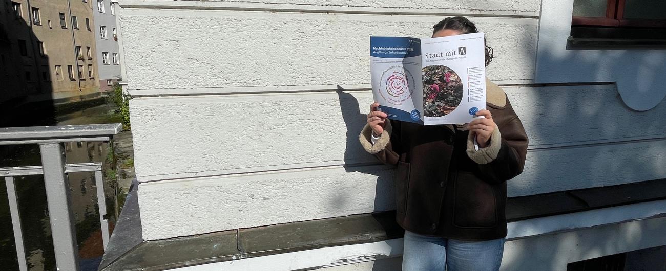 Frau liest Agendazeitung Stadt mit A