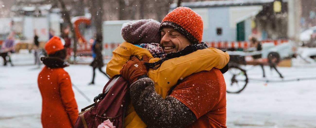 Zwei Menschen umarmen sich im Schnee auf einem Platz in Augsburg.