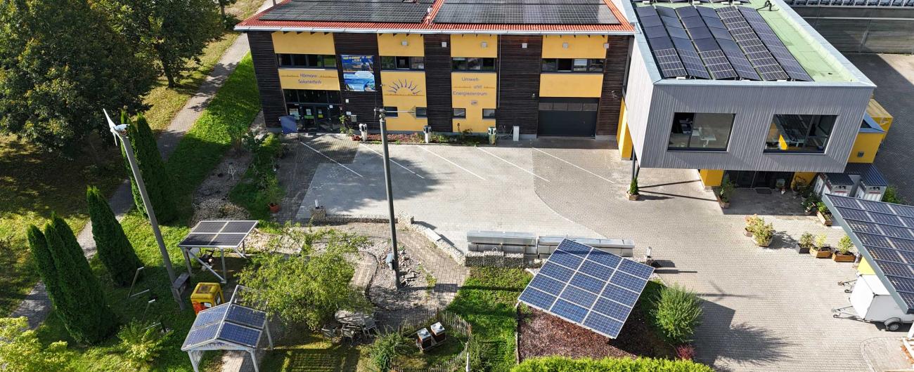 Luftaufnahme des Firmengeländes von Hörmann Solartechnik mit Photovoltaikanlagen auf dem Dach und Solarmodul-Ausstellung im Außenbereich.