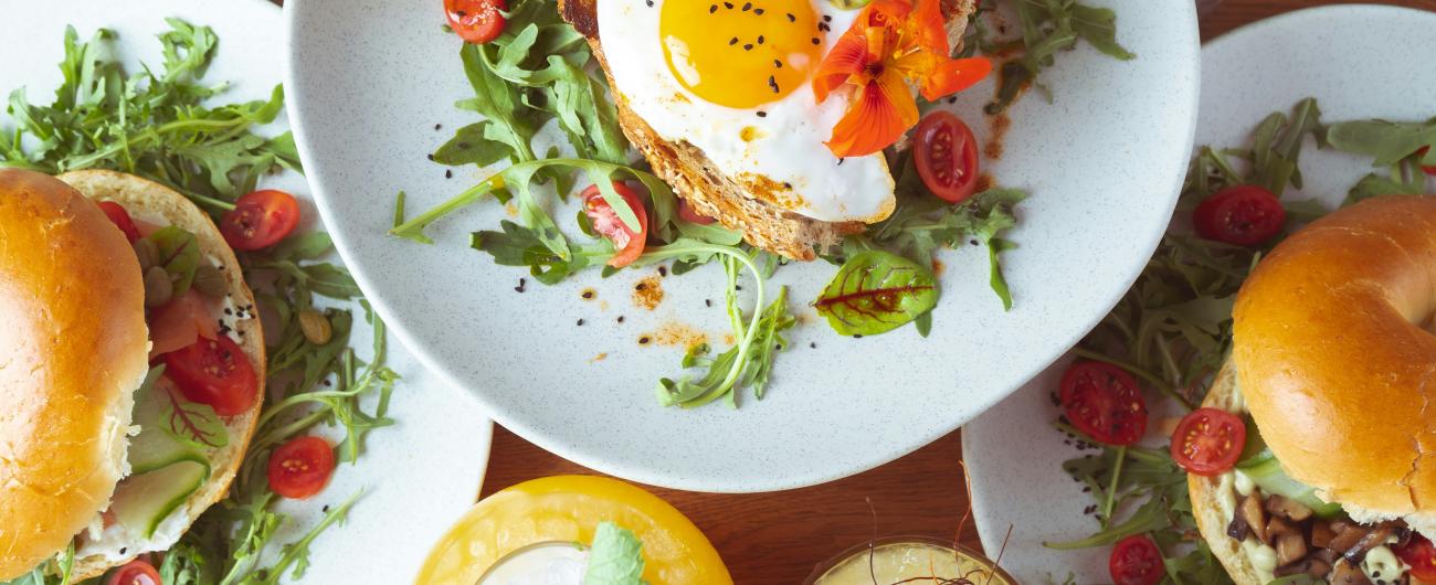 Detail eines Brunchs mit Eiern, Tomaten, Gemüse, Toast und Bagels.   