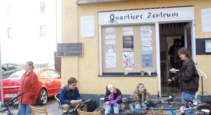 Personen sitzen vor dem Quartiers Zentrum in der Wiesenstraße Augsburg.