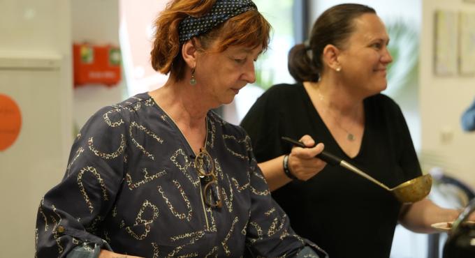 Helferinnen verteilen während des Projekts Knödel &amp; Kniffel das gerettete Essen aus der KUKA Betriebskantine auf die Teller.