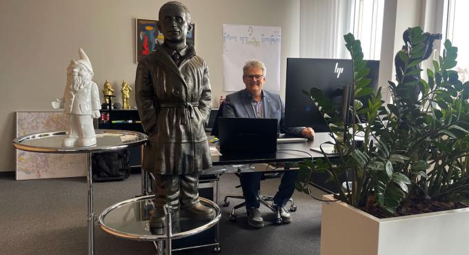 swa Chef Rainer Nauerz an seinem Schreibtisch zwischen einer Figrur von Bert Brecht und großen Gartenzwergen. Foto: Sylvia Schaab
