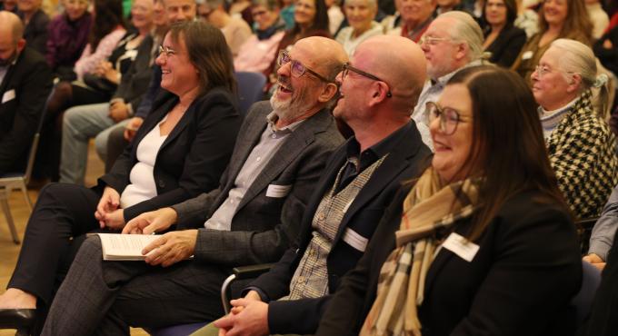 Foto des Publikums bei der Preisverleihung des Augsburger Zukunftspreises 2025. Das Publikum amüsiert sich.