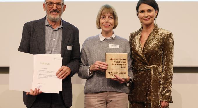 Foto des Zukunftspreises zur Förderung des gesellschaftlichen Zusammenlebens an die Augsburger Volkshochschule mit Umweltreferent Reiner Erben und Vorsitzenden des Integrationsbeirats Didem Karabulut.
