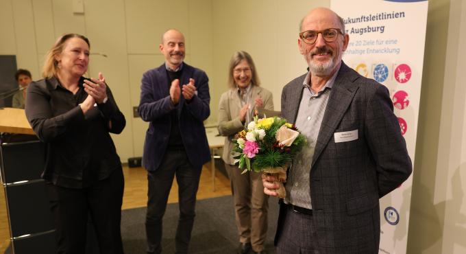 Foto von Reiner Erben mit einem Blumenstrauß in der Hand. Er lächelt direkt in die Kamera.