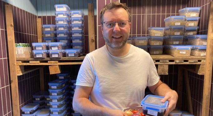 Ein Abholer im Abholraum der Foodcoop des Genusskollektiv Augsburg e.V. vor Regalen mit sauber abgepackten Lebensmitteln zum Abholen. © Genusskollektiv