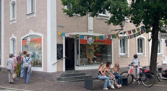 Aufnahme vom Weltladen in Aichach von der Strasse aus mit Menschen im Vordergrund